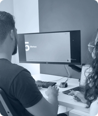 Foto dos colaboradores da Capulo olhando para uma tela de computador escrito "metas".