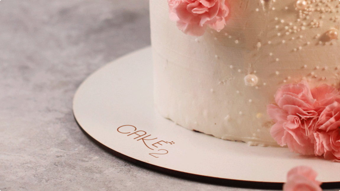 Foto mostra identidade visual aplicadaa a um suporte para bolos da empresa Cake 2 confeitaria afetiva.